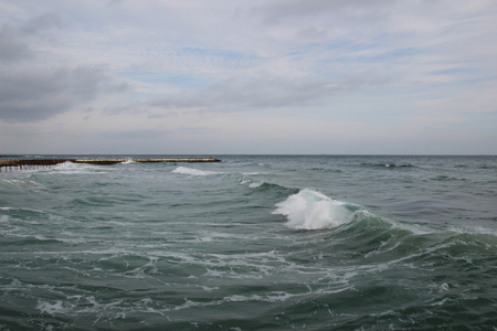 Empty beach of the North Sea in cloudy autumn weather. Landscape with stormy sea waves break about the empty wild beach against the cloudy sky on overcast dayの写真素材