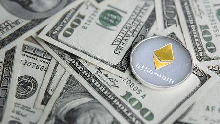 Ethereum crypto currebcy on US dollars. Digital currency close-up. Virtual money. Metal coins of Ethereum on banknotes of one hundred dollars. Exchange. Bussiness, commercial.の写真素材