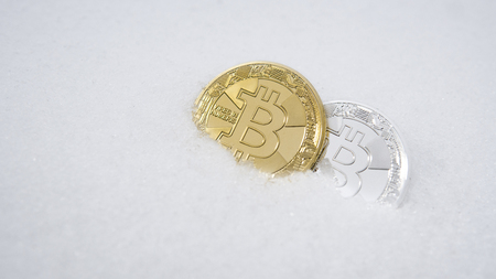 Gold and silver bitcoin. Cryptocurrency on snow, in the background. The concept of freelancing, the stock exchange. Gold bitcoin on cold winter snow background. Frozen bitcoin. Frozen account.の写真素材