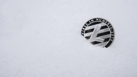 Silver Litecoin cryptocurrency on snow, in the background. The concept of freelancing, the stock exchange. Gold bitcoin on cold winter snow background. Frozen bitcoin. Frozen account.の写真素材