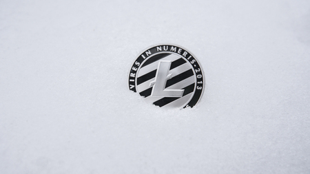 Silver Litecoin cryptocurrency on snow, in the background. The concept of freelancing, the stock exchange. Gold bitcoin on cold winter snow background. Frozen bitcoin. Frozen account.の写真素材
