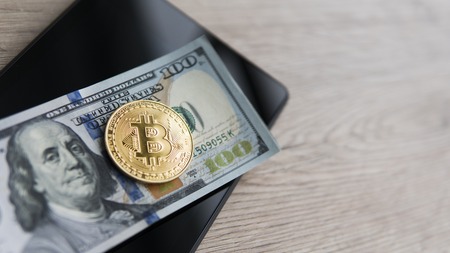 Golden bitcoins on a us dollars and on the tablet. Bitcoin crypto currebcy on US dollars. Digital currency. Virtual money. Metal coins of bitcoin on banknotes. Bussiness, commercial.の写真素材