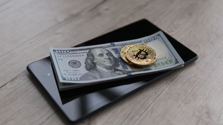 Two golden bitcoins on a us dollars and on the tablet. Bitcoin crypto currebcy on US dollars. Digital currency. Virtual money. Metal coins of bitcoin on banknotes. Bussiness, commercial.の写真素材