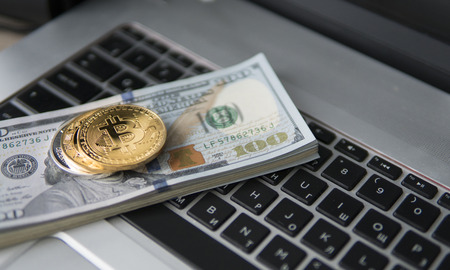 Bitcoin coin with laptop and us dollars. Bitcoin golden coins on a dollar banknotes office background white laptop mobile. Digital crypto currency. Metal coins of bitcoin. Bussiness, commercial.の写真素材