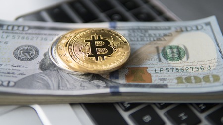 Bitcoin coin with laptop and us dollars. Bitcoin golden coins on a dollar banknotes office background white laptop mobile. Digital crypto currency. Metal coins of bitcoin. Bussiness, commercial.の写真素材