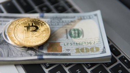 Bitcoin coin with laptop and us dollars. Bitcoin golden coins on a dollar banknotes office background white laptop mobile. Digital crypto currency. Metal coins of bitcoin. Bussiness, commercial.の写真素材