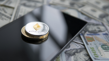 Ethereum coin on a golden Bitcoins and tablet on US dollars. Digital currency close-up. New virtual money. Crypto currency top view. Ethereum on banknotes of one hundred dollars. Bussiness.の写真素材