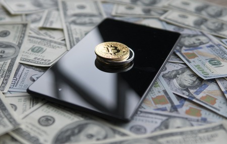 Bitcoins on a us dollars and on the tablet. Bitcoin crypto currebcy on US dollars. Digital currency. Virtual money. Metal coins of bitcoin on banknotes. Bussiness, commercial.の写真素材