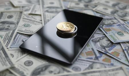 Bitcoins on a us dollars and on the tablet. Bitcoin crypto currebcy on US dollars. Digital currency. Virtual money. Metal coins of bitcoin on banknotes. Bussiness, commercial.の写真素材