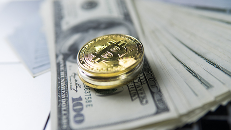 Bitcoin coin with laptop and us dollars. Bitcoin golden coins on a dollar banknotes and laptop. Cryptocurrency investment concept. BTC coin as symbol of electronic virtual money.の写真素材