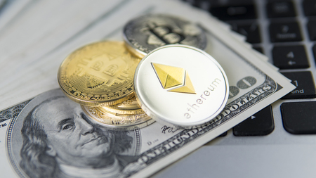 Ethereumcryptocurrency on a top of bitcoins and one hundred dollar bills on laptop. Profit from mining crypto currencies. BTC coin as symbol of electronic virtual money.の写真素材