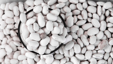 Close up on a raw organic white black beans in a glass with bean background. Macro. Healthy dietary...