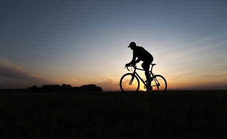 Silhouette of cyclist in motion on the background of beautiful sunset. Male ride bicycle in sun set. Silhouette of man biker ride a bike on sunsets sky on a field. Healthy Lifestyle. Sport.の写真素材