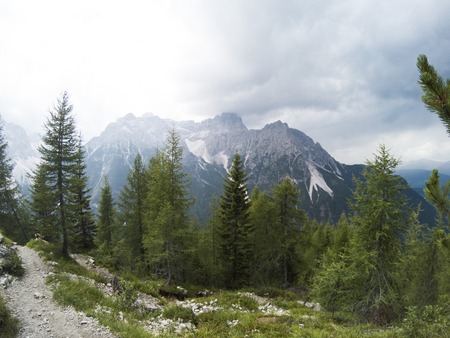 View fron a top of the mountain on a beautiful landscape of Dolomites moutains and a gree coniferous forest in front in rain weather. South Tyrol, Italy, Alp. Captured on action camera.の写真素材