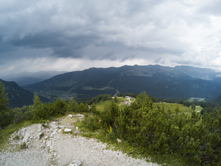 Beautiful view on landscape of Dolomites moutains and a gree forest with a with small houses in the valley. South Tyrol, Italy, Alp. Captured on action camera. Weather before a rainの写真素材