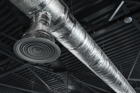Ventilation system on the ceiling of large buildings. Ventilation pipes in silver insulation material hanging from the ceiling inside new building.の写真素材