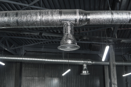 Ventilation system on the ceiling of large buildings. Ventilation pipes in silver insulation material hanging from the ceiling inside new building.の写真素材