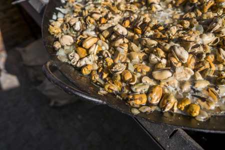 Fresh mussels at grill pan. Seafood barbecue outdoors. Picnic healthy food, mussels without a shells. Seafood, grilled appetizing mussels on a black plate.の写真素材