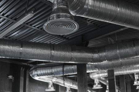 Ventilation system on the ceiling of large buildings. Ventilation pipes in silver insulation material hanging from the ceiling inside new building.の写真素材
