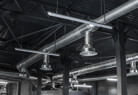 Ventilation system on the ceiling of large buildings. Ventilation pipes in silver insulation material hanging from the ceiling inside new building.の写真素材