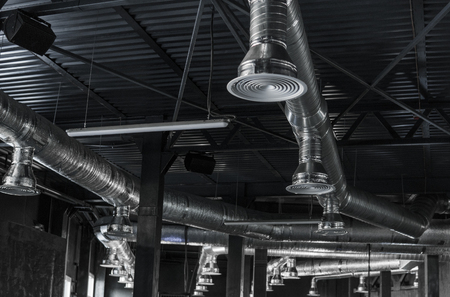 Ventilation system on the ceiling of large buildings. Ventilation pipes in silver insulation material hanging from the ceiling inside new building.の写真素材