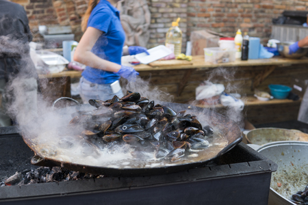 Fresh mussels at grill pan. Seafood barbecue outdoors. Picnic healthy food, mussels in shells. Plenty of mussel shells cooking at large metallic pan.の写真素材