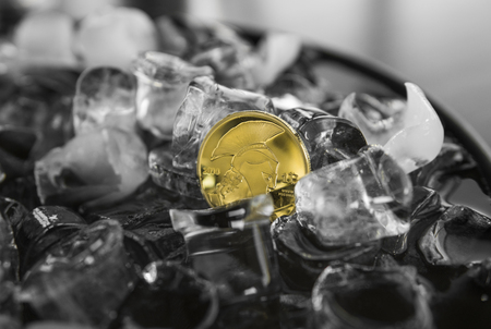 Gold Titan coin on ice background. Blockchain mining. Digital money and virtual crypto currency concept.の写真素材