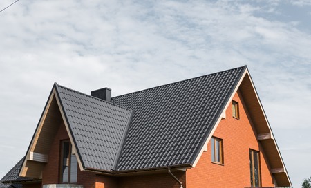 Modern roof covered with tile effect PVC coated brown metal roof sheets.の写真素材