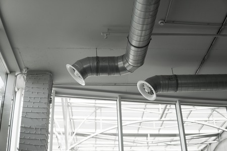 Ventilation system on the ceiling of large buildings. Ventilation pipes in silver insulation material hanging from the ceiling inside new building.の写真素材