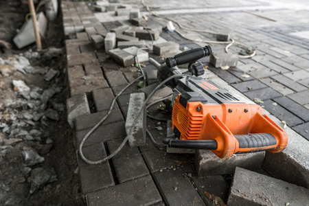 Electric Concrete Breaker laying on a road of cobblestone during sidewalk construction works.