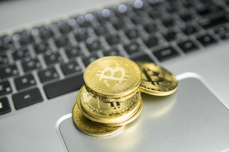 A stack of golden bitcoin coin on a silver keyboard of laptop. Virtual cryptocurrency concept. Mining of bitcoins online bussiness. Bitcoins trading.の写真素材