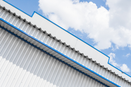 Industrial construction of Metal white sheet and blue corners. Roof sheet metal or corrugated roofs of factory building or warehouse.の写真素材
