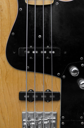 Close up of electrical bass guitar fingerboard. Wooden bass with volume controller.