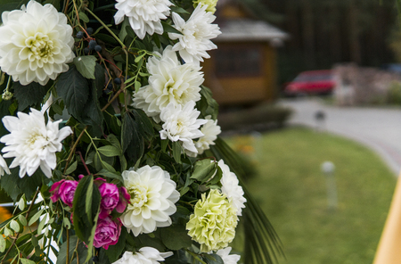 Flower as a decoration on a wedding. Floral wooden arch with yellow cloth and fresh white flowers with green leaves on a rustic wedding ceremony.の写真素材