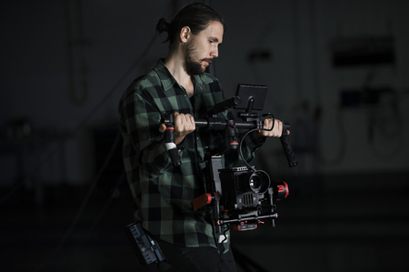 Professional videographer holding camera on 3-axis gimbal. Videographer using steadicam. Pro equipment helps to make high quality video without shaking.の写真素材