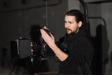 Professional videographer holding camera mounted on easy rig. Videographer using steadicam. Pro...