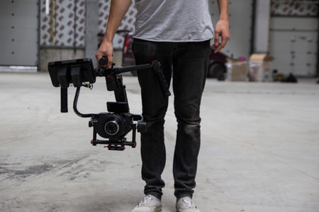 Professional videographer holding camera on 3-axis gimbal. Videographer using steadicam. Pro...