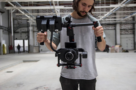 Professional videographer holding camera on 3-axis gimbal. Videographer using steadicam. Pro...