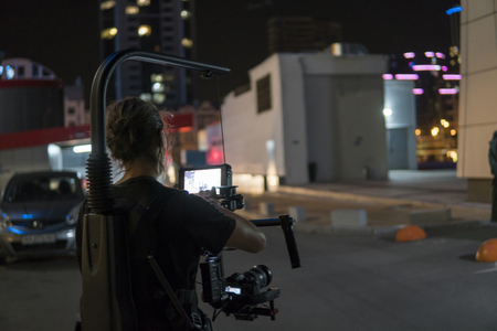 Professional videographer holding camera on 3-axis gimbal which mounted on easy rig. Videographer using steadicam. Pro equipment helps to make high quality video without shaking.の写真素材