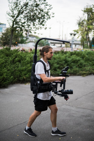 Professional videographer holding camera on 3-axis gimbal which mounted on easy rig. Videographer...