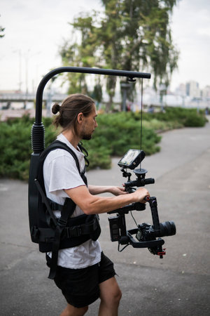 Professional videographer holding camera on 3-axis gimbal which mounted on easy rig. Videographer...