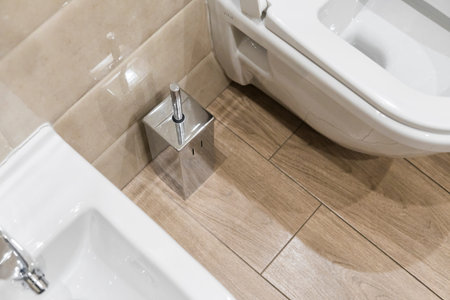 Details of white ceramic bidet and toilet with toilet brush in modern bathroom.