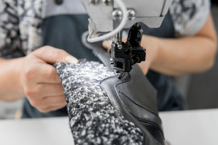 Sewing machine in a leather workshop in action with hands working on a leather details for shoes....