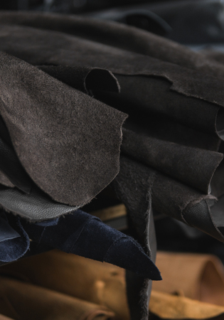 Different pieces of leather in a rolls. The pieces of the colored leathers. Rolls of natural brown and black and other leather. Raw materials for manufacture of bags, shoes, clothing and accessories.の写真素材