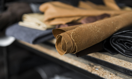 Different pieces of leather in a rolls. The pieces of the colored leathers. Rolls of natural brown red leather. Raw materials for manufacture of bags, shoes, clothing and accessories.の写真素材