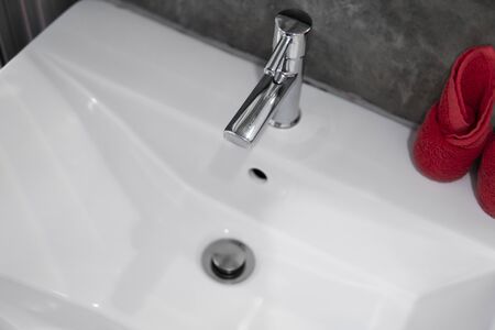 Modern stainless steel faucet with wash basin sink with a two red towels on it . Counter bathroom interior contemporary. Luxury and stylish design bathroom with a concrete style walls.の写真素材