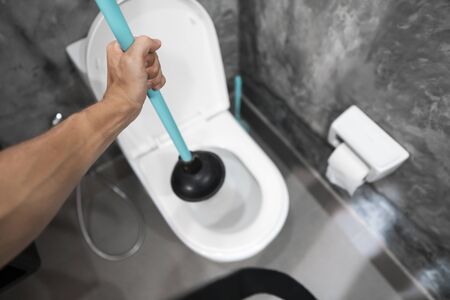 Toilet repair by hand with a Toilet Plunger. Plumbing. A plumber uses a plunger to unclog a toilet. Toilet Plunger.の写真素材