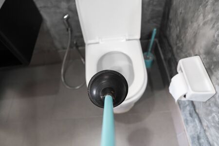 Toilet repair by hand with a Toilet Plunger. Plumbing. A plumber uses a plunger to unclog a toilet. Toilet Plunger.の写真素材