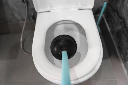 Toilet repair by hand with a Toilet Plunger. Plumbing. A plumber uses a plunger to unclog a toilet. Toilet Plunger.の写真素材