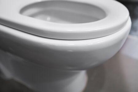 White hanging toilet seat on white toilet in the home bathroom with grey tiles in concrete style. Bathroom luxury interior.の写真素材